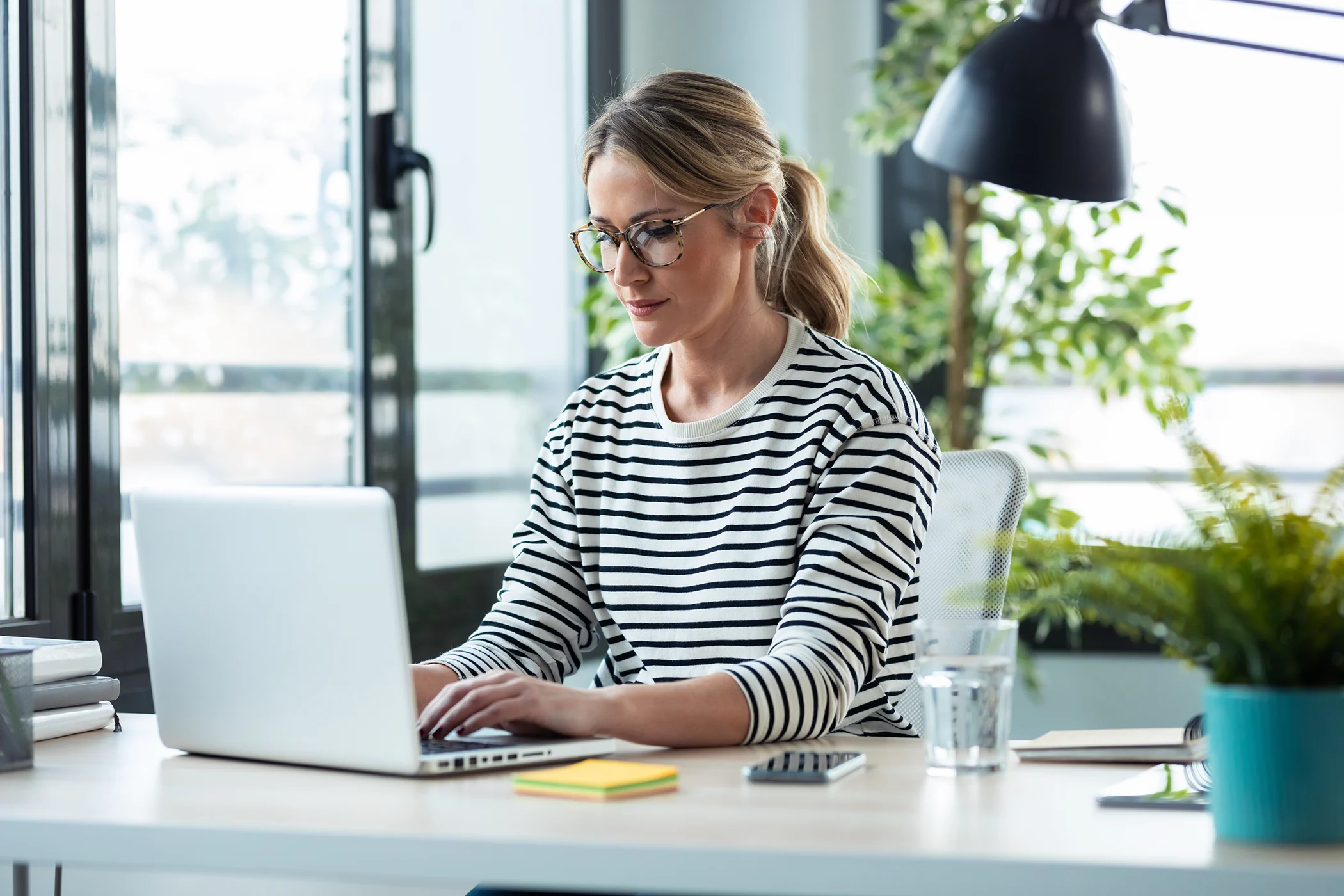 woman working while typing with a laptop on a desk